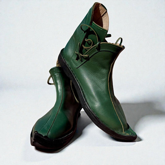 Handmade green medieval leather boots with wrap laces, visible stitching, and full-grain texture, ideal for LARP or SCA reenactment.